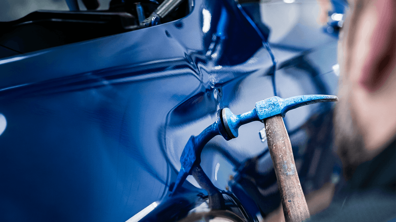 Carrossier Mercedes-Benz Kroely travaillant sur le débosselage d'une voiture