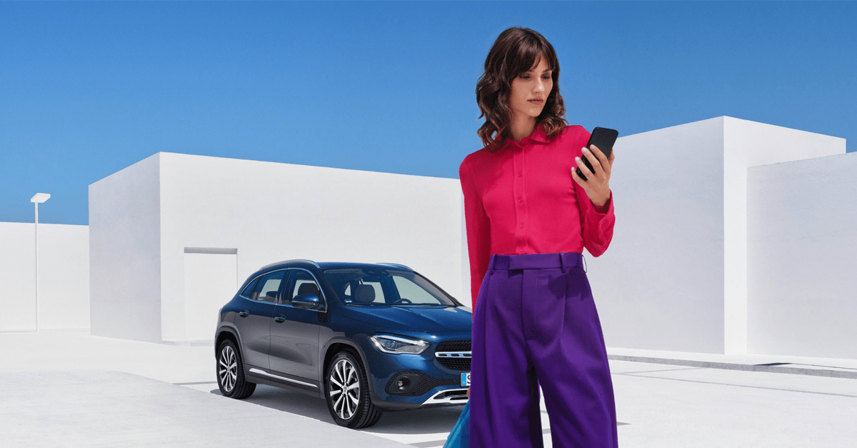 femme sur son smartphone après avoir stationné son véhicule Mercedes