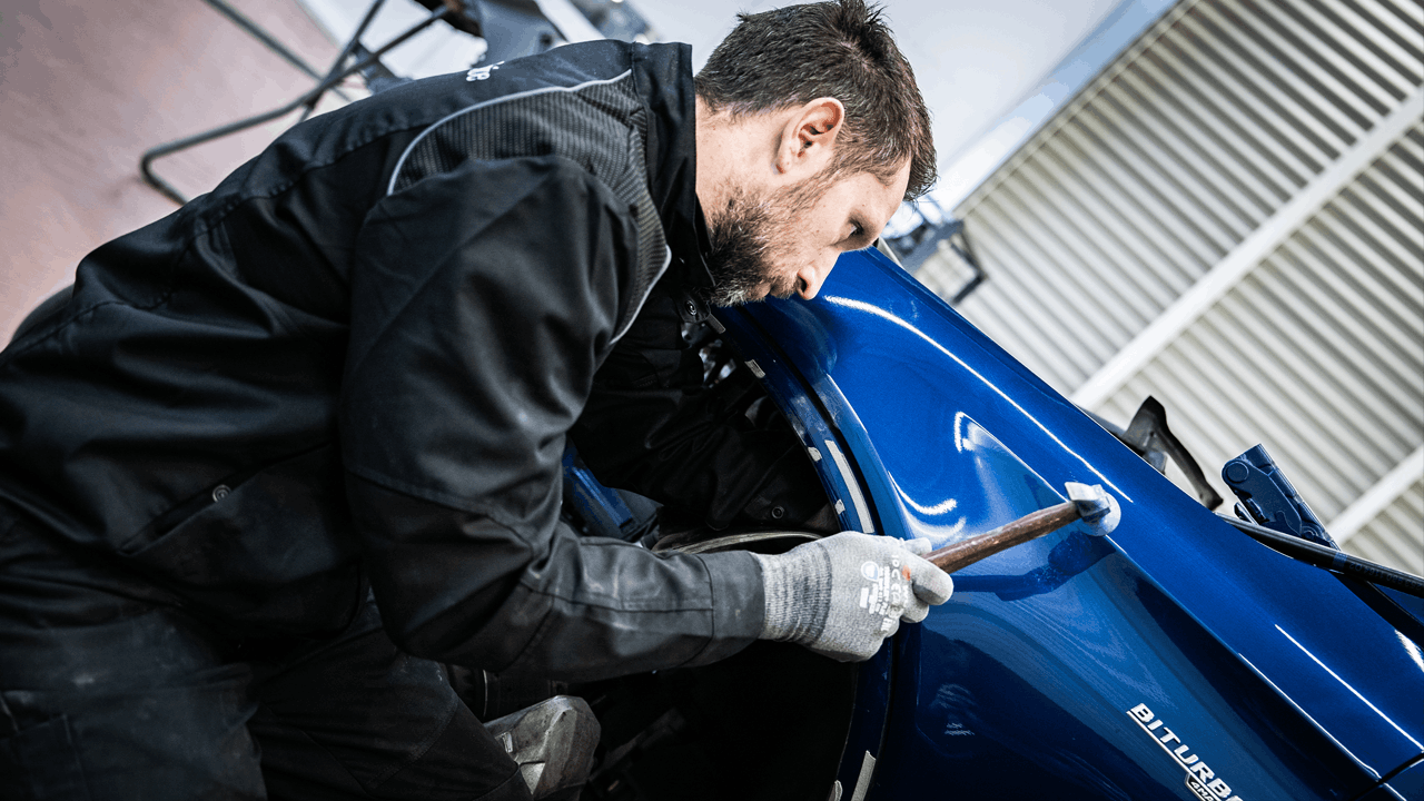 Carrossier Mercedes-Benz Kroely travaillant sur le débosselage d'une voiture